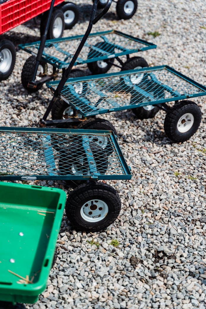 From above of small carts with black wheels and metal grid placed on stone ground in daytime